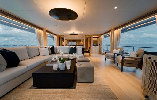Main salon onboard luxury yacht rental SEA-RENITY, lounge and L-shaped seating to port with armchairs starboard
