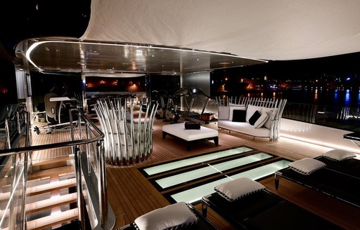 A collection of sleek furnishings and gymnasium equipment on the sundeck of a superyacht at night