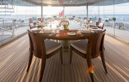 Alfresco dining set up onboard charter yacht JOIA THE CROWN JEWEL, long table surrounded by wooden seats, laid for a meal