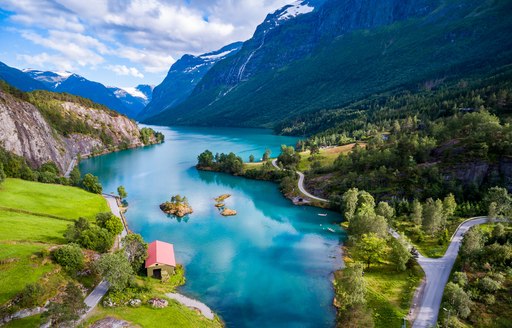Small houses on a bank of a fjord with majestic mountains in the background in Norway