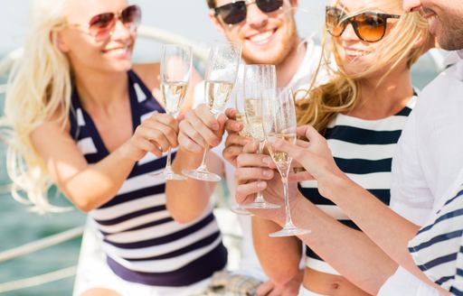 four friends on a superyacht clink champagne flutes 