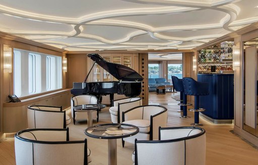 Grand piano and seating area onboard charter yacht DREAM, with multiple monochrome armchairs arranged