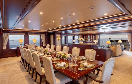 Interior formal dining setup with long table and cream upholstered chairs onboard superyacht charter GIGIA