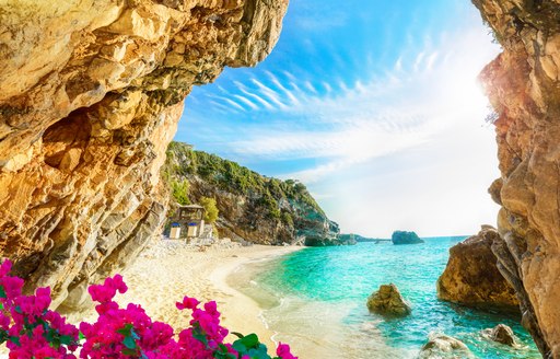 Beautiful beach in Corfu with a rocky arch and pink bougainvillea the foreground