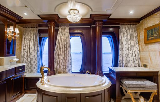 Private bathroom attached to the master cabin onboard charter yacht PURPOSE, central circular bath with large windows and a sink unit to port side