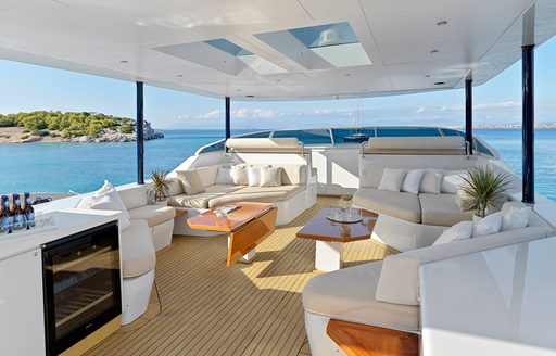 Overview of the flybridge onboard charter yacht Mia Zoi, with a wet bar forward and a plush lounge area aft, surrounded by sea