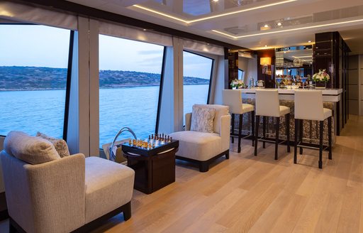 Interior wet bar and games table onboard charter yacht AQUA LIBRA with adjacent windows