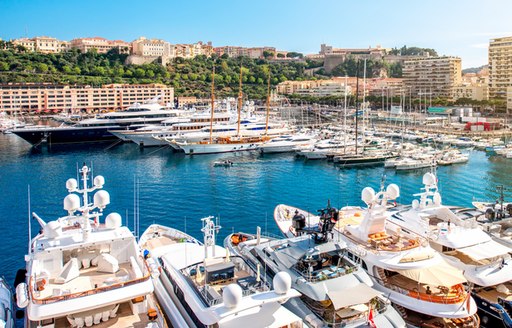 Motor yachts moored in Monaco marina, with hotels and facilities around dockside.