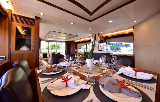 Formal dining area onboard charter yacht CATALANA, surrounded by large windows.