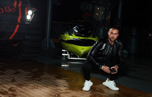 Philipp Plein crouching in front of tender on Explorer yacht RAGNAR