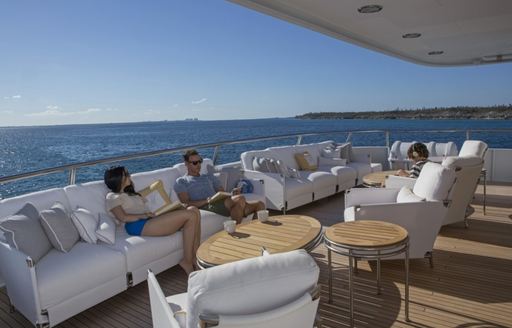 Guests relaxing on outside deck of explorer yacht MARCATO with sea in background