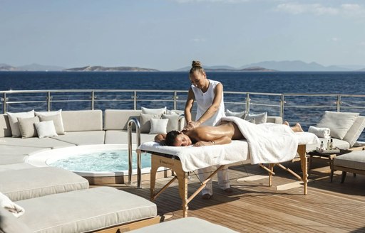 A female charter guest receiving a massage treatment on the exterior deck of luxury charter yacht EMIR