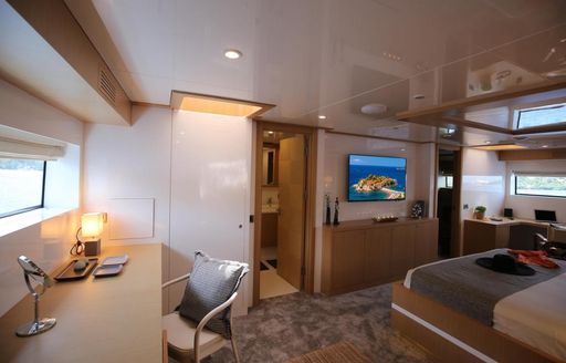 View into cabin on Superyacht Ottawa IV with large flatscreen TV on wall and door into ensuite