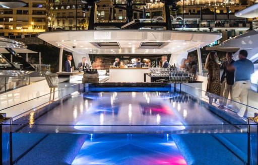 Pool on superyacht SEVERIN'S at night with guests standing talking