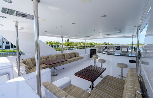 Overview of the flybridge onboard charter yacht NEXT CHAPTER, with alfresco dinette in the foreground and a wet bar with stools aft