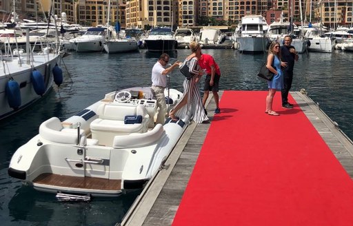 Women and men leaving a tender to step onto a red carpet port