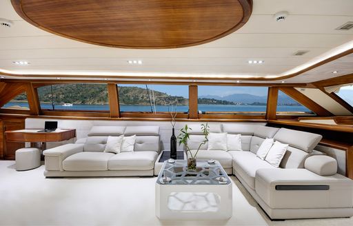 Plush lounge seating in the main salon onboard sailing yacht charter ALESSANDRO I, surrounded by large windows