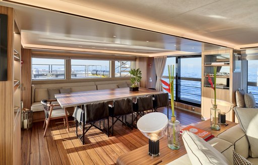 Interior dining area onboard charter yacht PARA BELLUM, long dining table with chairs and surrounded by large windows