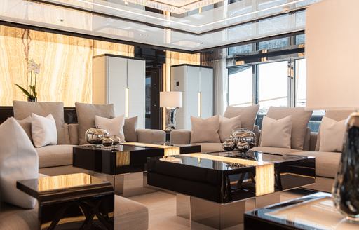 Main salon onboard charter yacht RESILIENCE, plush gray seating surrounding low, black coffee tables