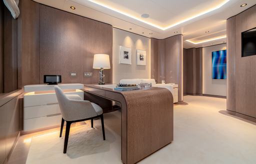 Chair behind table on superyacht O'PARI, with lightly colored furnishing