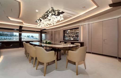 Dining table and chairs on superyacht O'PARI with intricate lighting above