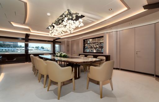 Dining table and chairs on superyacht O'PARI with intricate lighting above