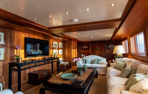 Large flat screen TV on superyacht 'Bleu De Nimes' with comfortable cream sofa and wooden table facing it