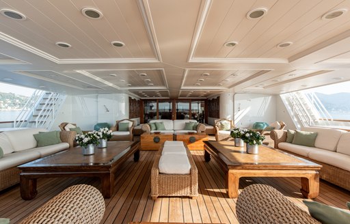 Undercover seating area on superyacht 'Bleu De Nimes', with cream sofas and wooden tables