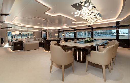 Large salon on superyacht O'PARI, showing open plan room with table and chairs in foreground and sofa and table in background