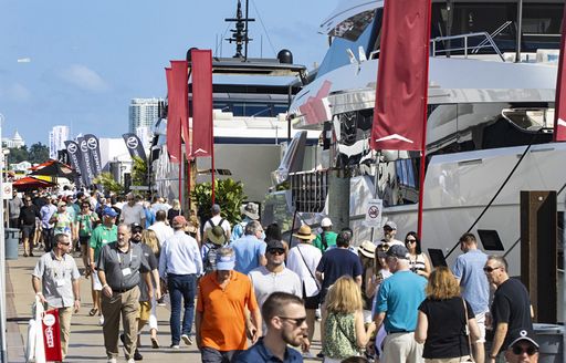 Visitors walking alongside berthed motor yachts at the Miami International Boat Show