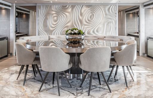 Circular dining table with chairs seated around circumference and ornamental display in middle of table on superyacht SEVERIN'S