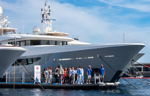 A superyacht charter berthed at the Monaco Yacht Show with visitors gathered on the adjacent pontoon