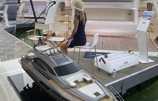 a spokeswoman sitting on the platform of a grand superyacht that is being showcased in the miami yacht show 2020 in Florida
