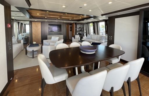 Interior dining setup onboard charter yacht SPORT, long table surrounded by eight white chairs 