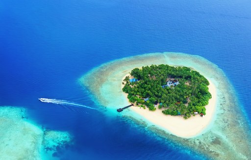 View of Maldives island from above with boat moving away from it