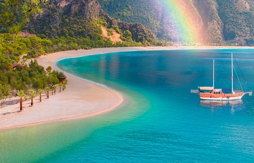 Gulet anchored in a secluded bay in Turkey with a rainbow in the background