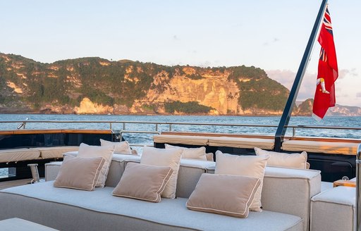 Seating arranged on the aft deck of private yacht charter GALILEO, with surrounding views of elevated terrain in the background