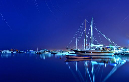 Gulets anchored in a marina in Turkey at night against a beautiful dark blue sky