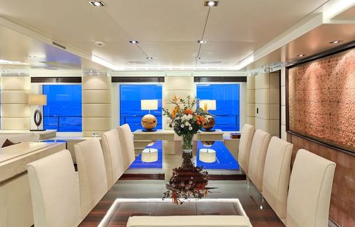 Interior dining table surrounded by white upholstered chairs onboard charter yacht TIMBUKTU