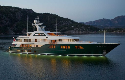 Charter yacht SEA OWL underway, with elevated terrain in the background