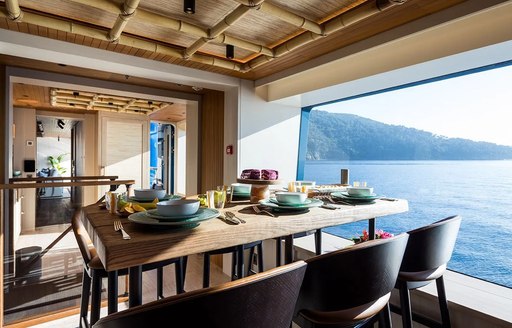 Interior dining area onboard charter yacht KING BENJI, table prepared for a meal adjacent to a large window