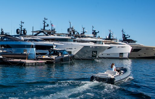 Line of superyachts berthed at Vieux Port, with a tender running in the foreground