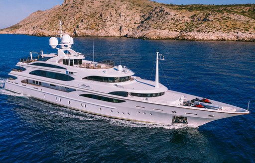 Charter yacht IDYLLIC underway with elevated terrain in the background