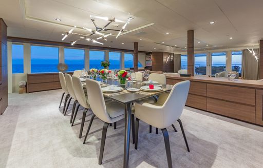 Interior dining setup onboard charter yacht BIG SKY, central dining table surrounded by 10 white upholstered seats