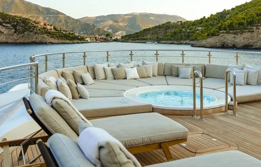 Overview of a deck Jacuzzi surrounded by sunpads and loungers onboard charter yacht EMIR