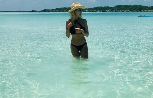 Woman with hat in swimwear standing in the water