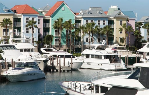 A marina on Paradise Island in the Bahamas, colored buildings in the background with motor yachts berthed forward