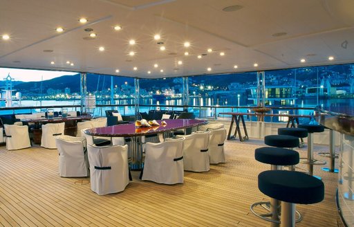huge alfresco dining area on board superyacht ‘Force Blue’ with two large tables and a bar