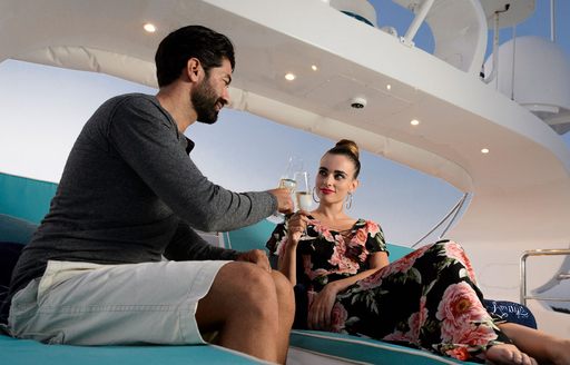 charter guests sip champagne while on the sun loungers aboard charter yacht AMAYA 