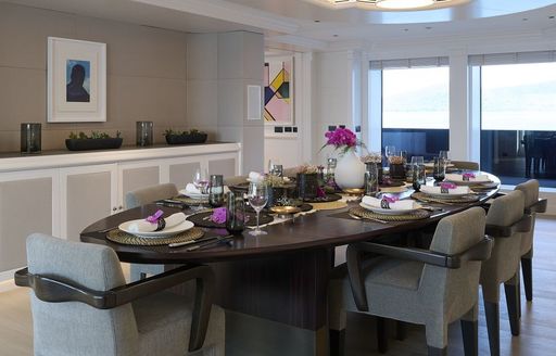 Interior dining area onboard charter yacht ARBEMA, long table set for a meal with large windows in the background